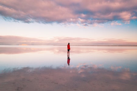 A person in a red jacket standing on the flooded Bonneville, Utah salt flats