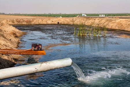 Groundwater pipe pumping water into holding pond