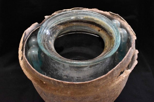 A photograph of the top opening of an ancient urn, over 2000 years old, on a black background