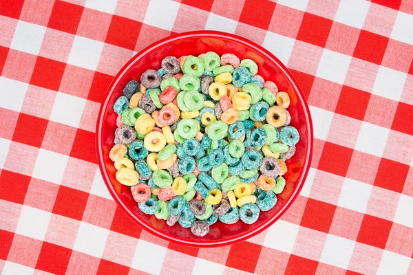 A red bowl of sugary, sweet looped grain cereal and milk on a classic, red, checkered tablecloth