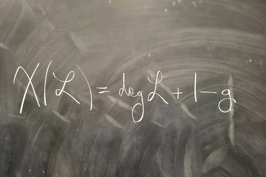 Math equation written in white on a black board.