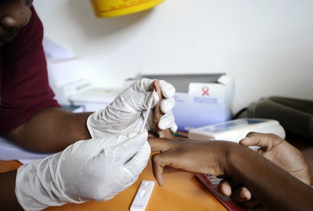 A nurse taking a blood sample from a person's finger.