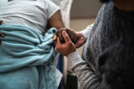 Son holding father's hand at the hospital