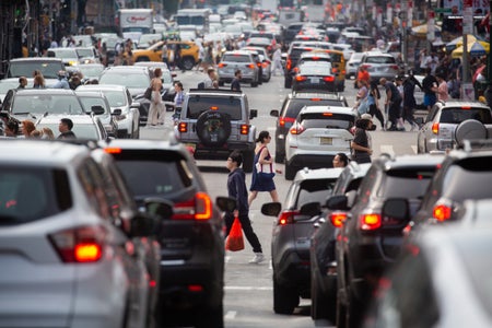 Pedestrians navigating between heavily congested traffic.