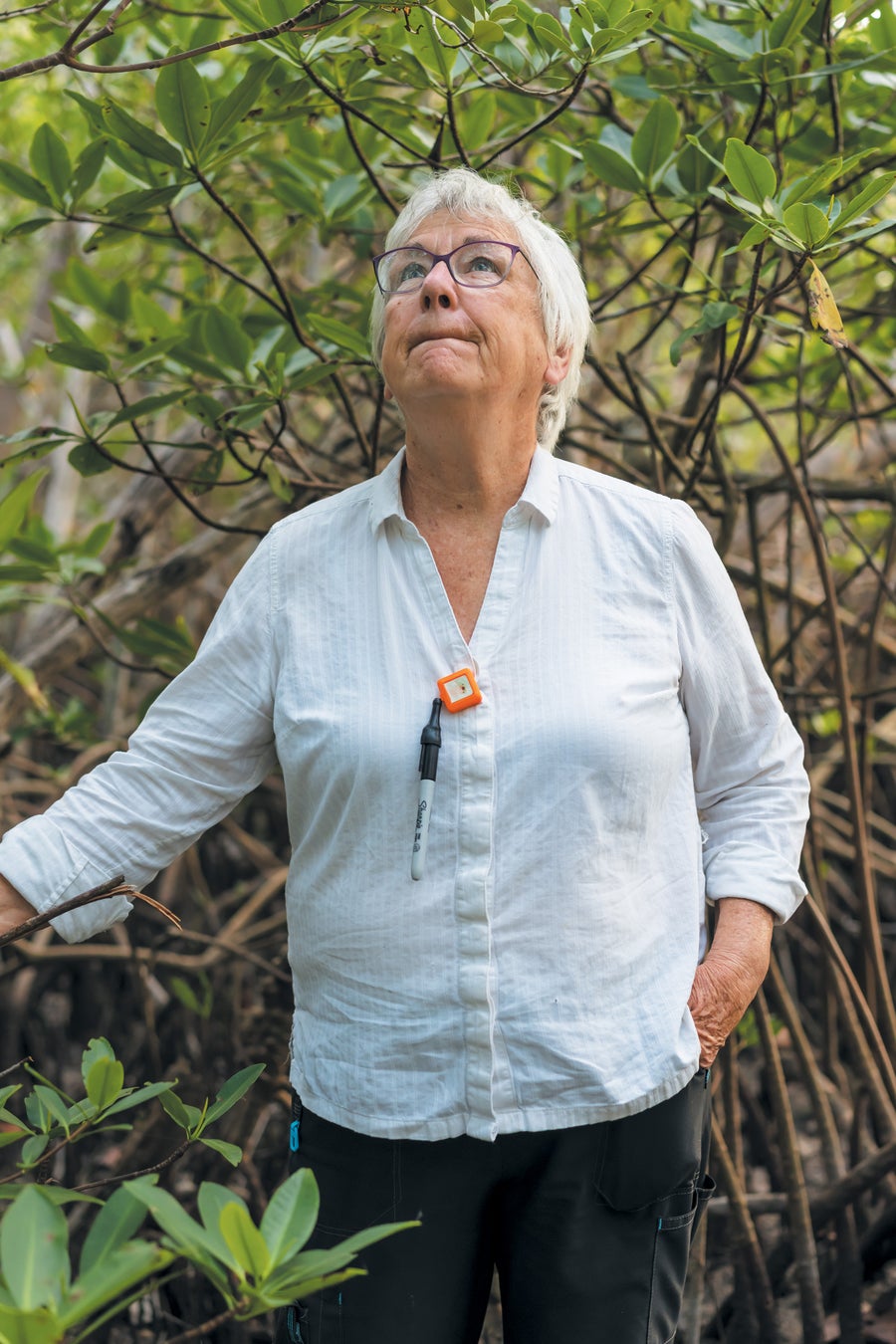 A woman standing outside with trees in the background.